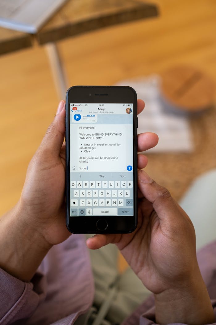 Close-up of hands holding a smartphone while typing a text message indoors.