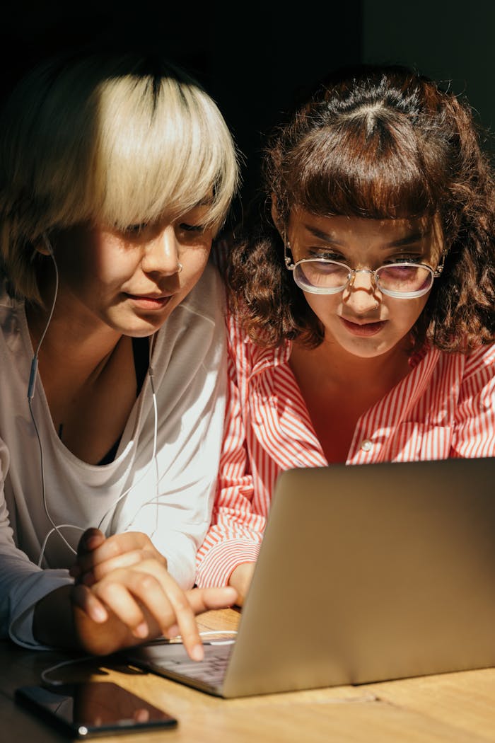 Two young women enjoying leisure time together using a laptop indoors.