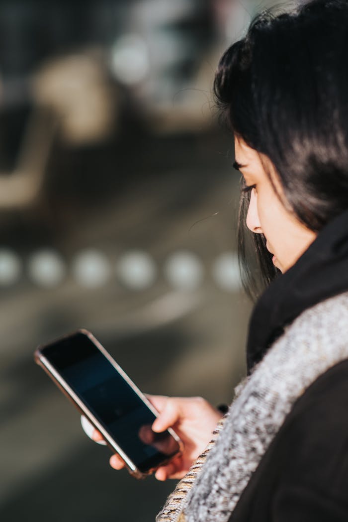 Side view of a woman texting on her smartphone outdoors.