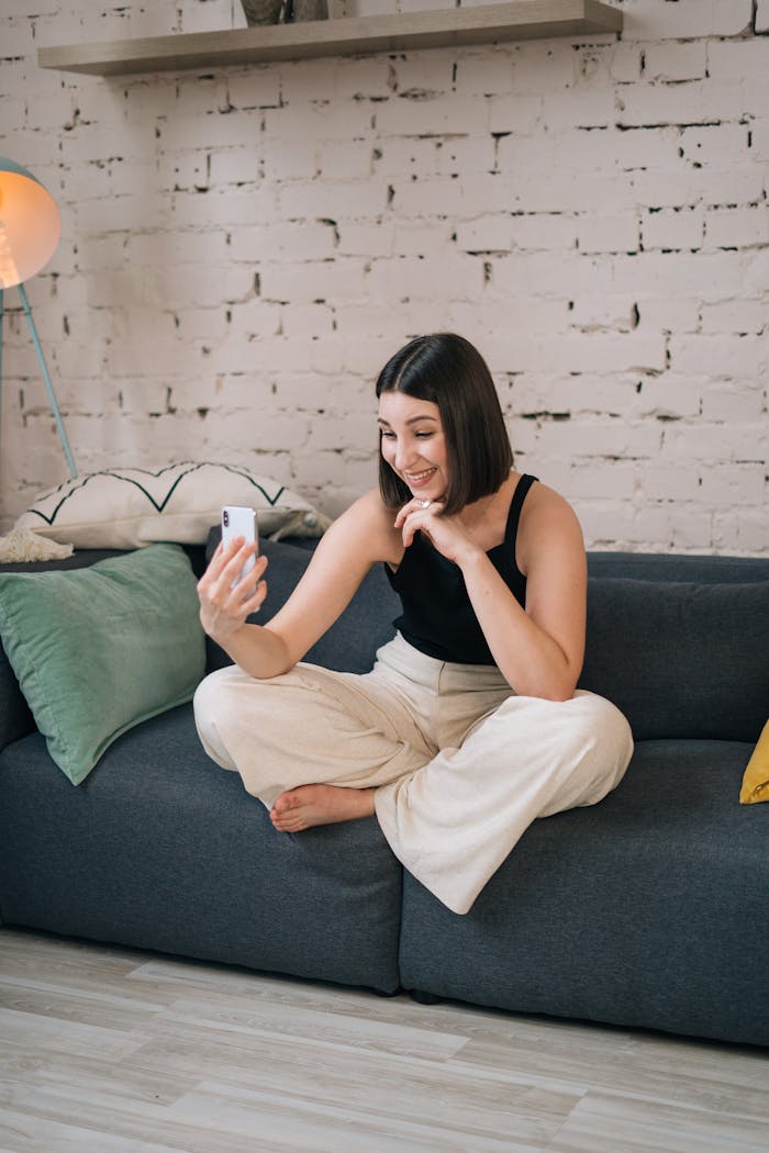 Smiling woman in a casual setting making a video call on a mobile device.